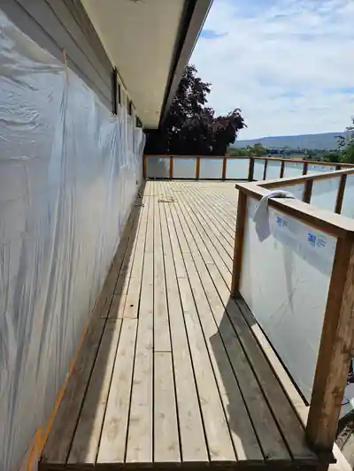 New deck boards before stain, with the house wall wrapped in plastic