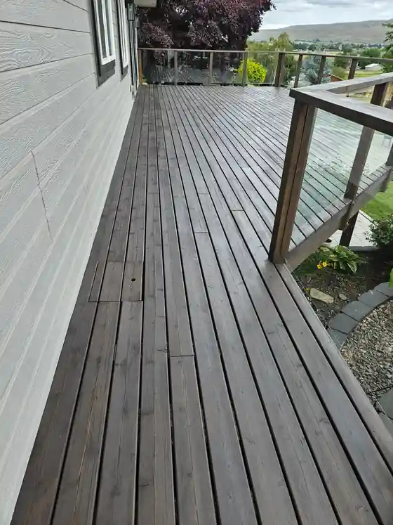 A finished grey-stained deck looking out over a valley