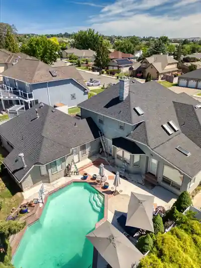 Aerial view of a large grey home with a pool