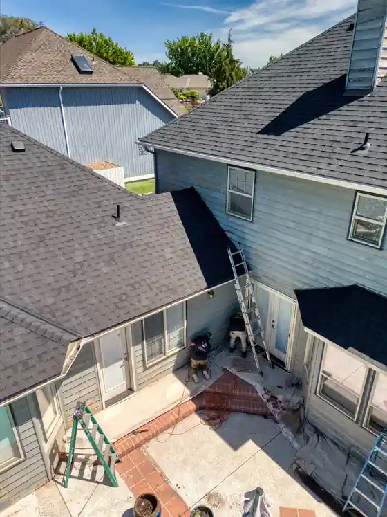 The same grey home from above, with ladders set up at the rear of the house