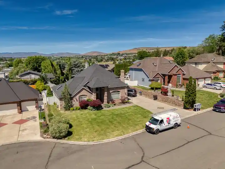 Aerial view of a cul-de-sac home with the white Top Line van out front and hills on the horizon
