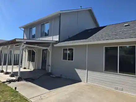 The back of a grey two-storey home with a patio cover