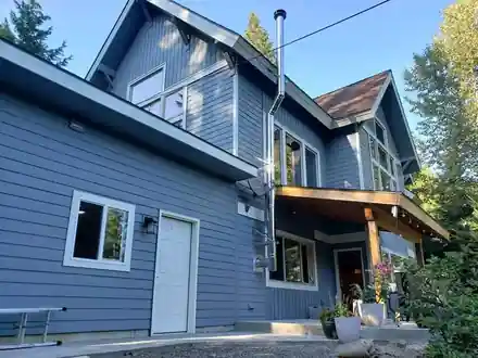A blue-grey two-storey craftsman home after its repaint