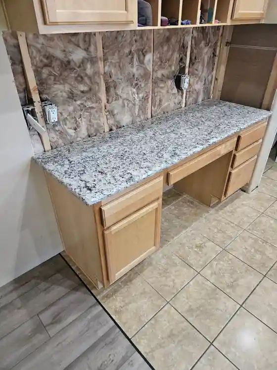 Granite countertop being installed with the wall still open and insulation visible