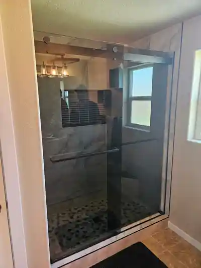 A walk-in shower remodel with marble-look tile and a glass door, seen from the side