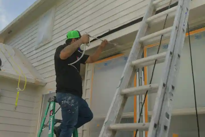 A Top Line painter on a ladder masking a window