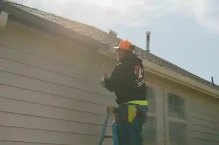 A painter at the gutter line in a Top Line hoodie